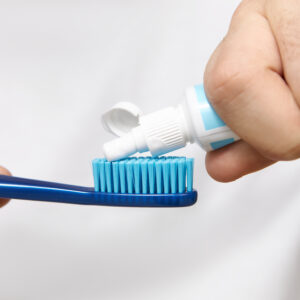 Close up image of man's hands holding tube, squeezing whitening toothpaste on brush. Cropped shot of young male going to clean oral cavity after having meal. Hygiene, care and healthy lifestyle